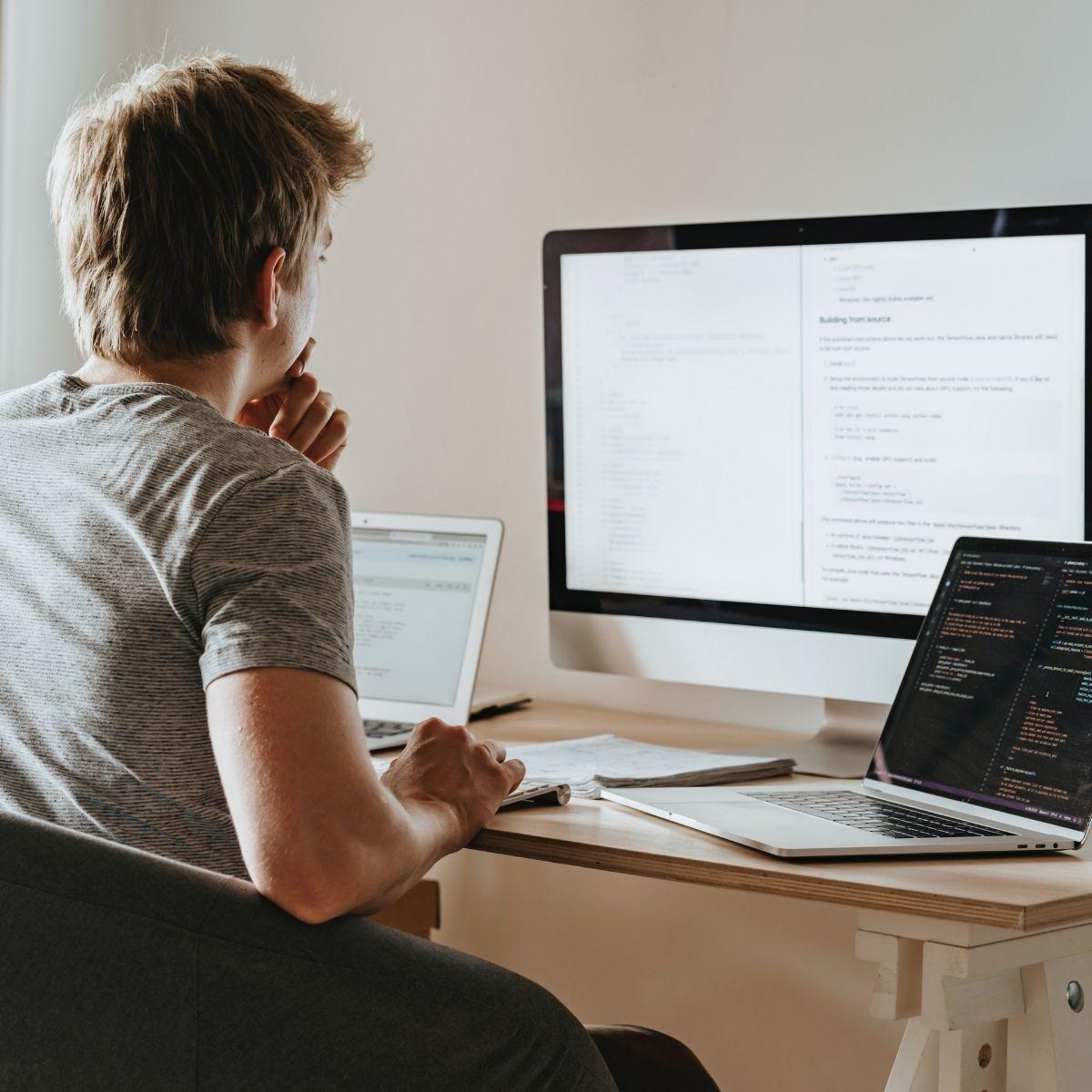 man sits at desk and looks at code