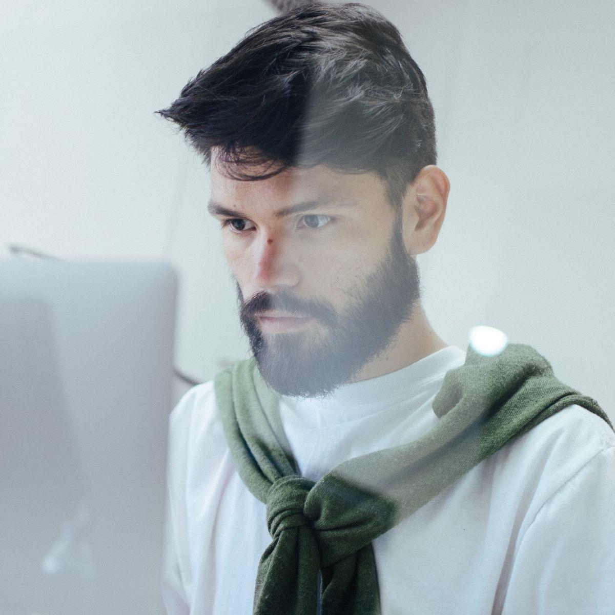 a man with a sweater looks at his computer screen