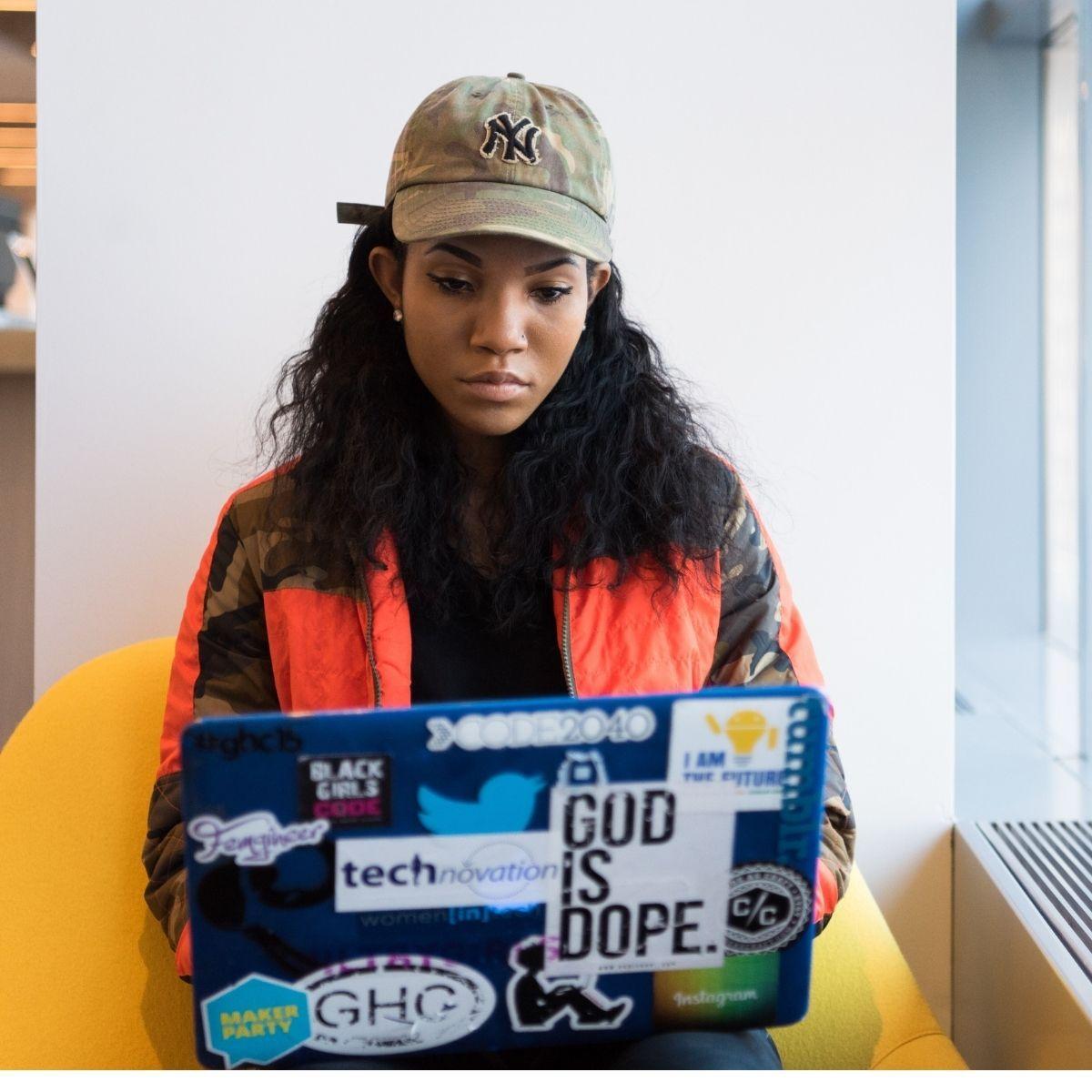woman looks at laptop covered in stickers